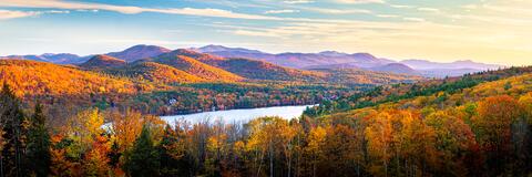 The rising sun lighting up the autumn covered mountains surrounding Little Squam Lake.
