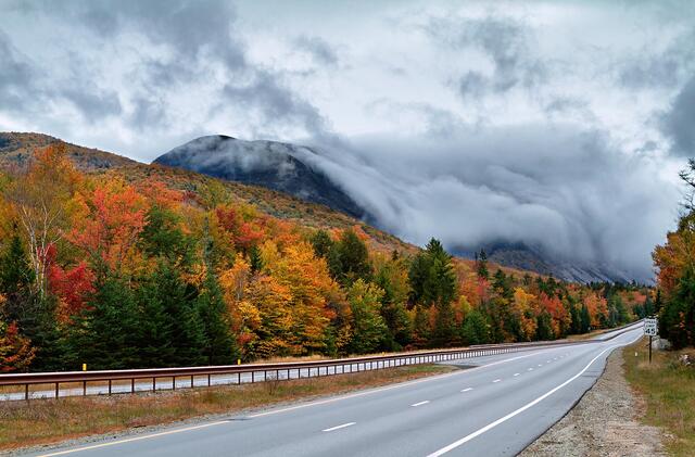 Rolling fog curled over Cannon Cliffs dressed for autumn in Franconia Notch State Park