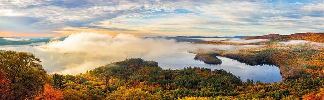 Fog lifts as the sun rises over Squam Lake in autumn