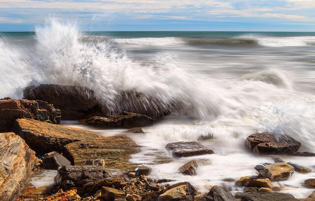 A storm wave crashes over the rocks about to get everyone wet in Rye, NH