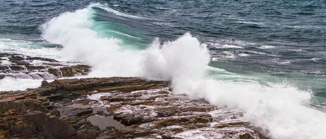 Storm wave crashes on the rocky shore in York, ME