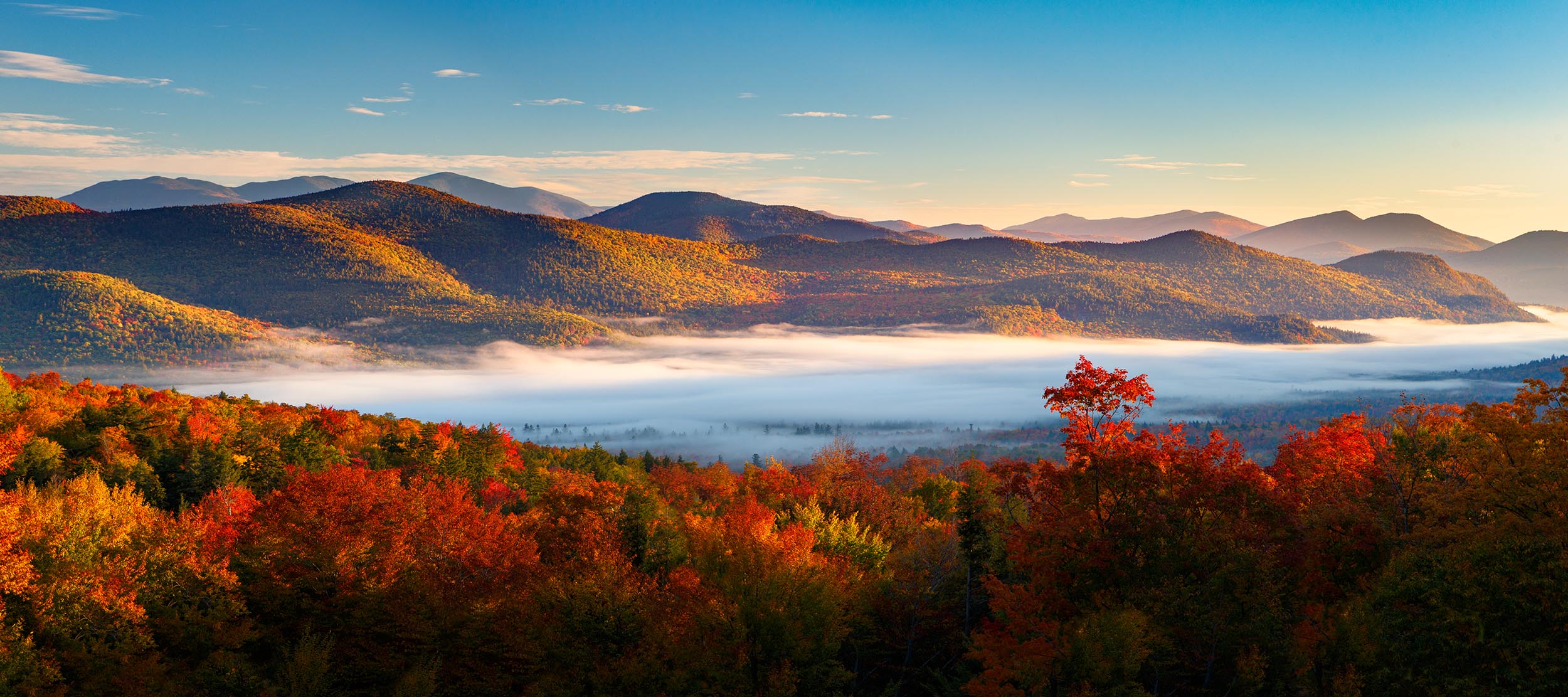 Sunrise Autumn Fog Over Bartlett. Bear Notch Road Fog blankets Bartlett as the rising sun lights up the mountains as seen from Bear Notch Rd.