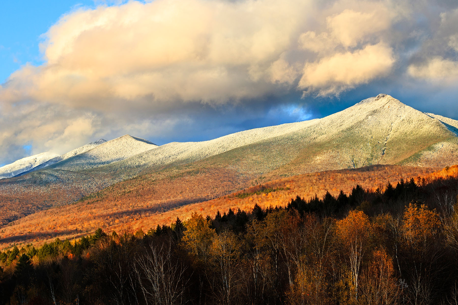 Franconia Mountains Evening Glow The setting sun lights up the Franconia Mountains snow covered peaks and paints the autum leaves an auburn glow.